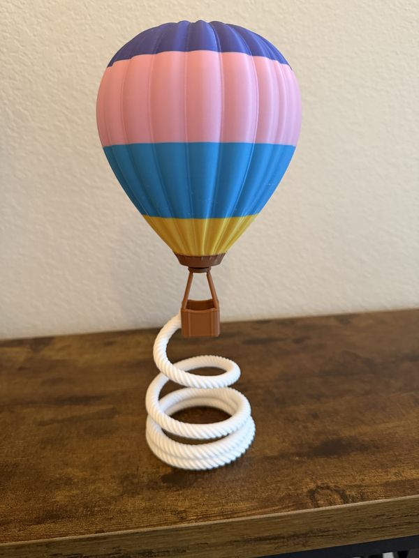 Striped 3D-printed hot air balloon standing on a white rope spiral