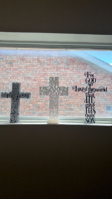Three 3D-printed crosses formed from the words of the Lord's Prayer and John 3:16, standing in a window