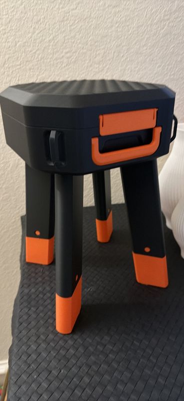 Black and orange 3D-printed stool with a built-in carry handle